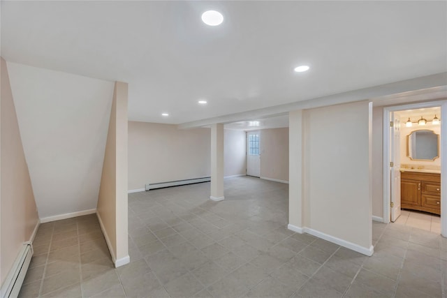 basement with light tile patterned floors, baseboard heating, and sink