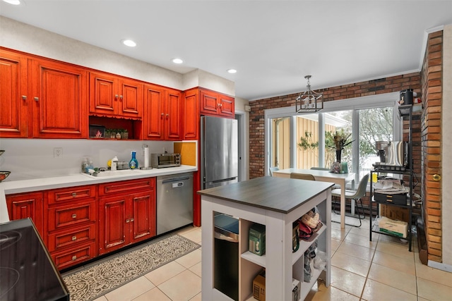 kitchen with decorative light fixtures, light tile patterned flooring, brick wall, and stainless steel appliances