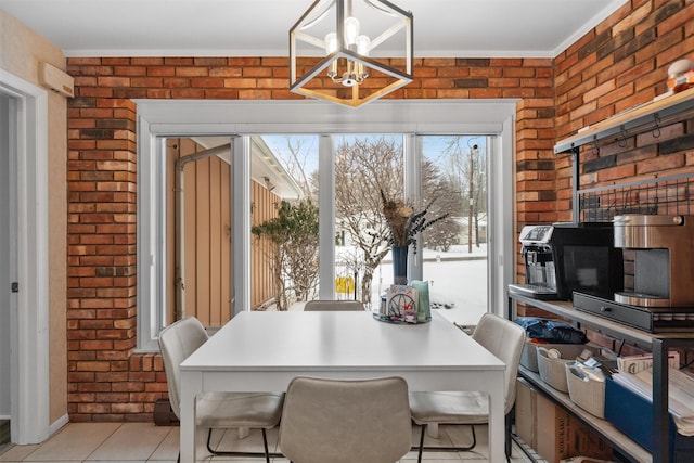 tiled dining space featuring brick wall and a chandelier