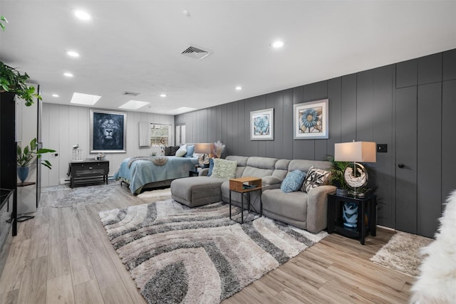 bedroom with light wood-type flooring, a skylight, and wood walls