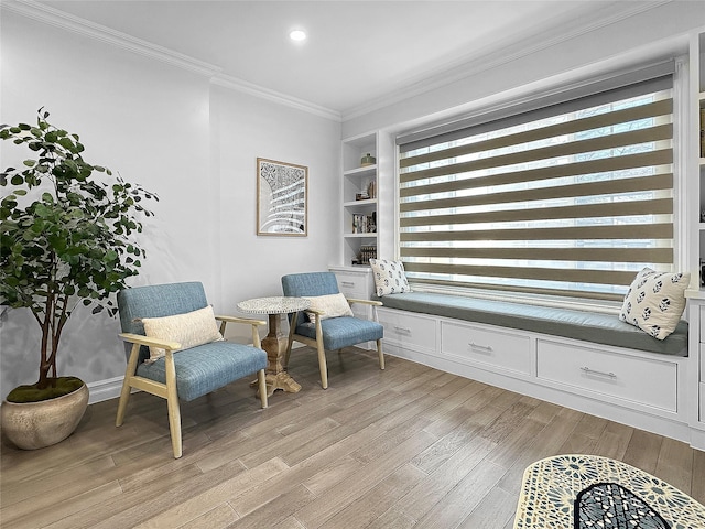 sitting room featuring built in shelves, light hardwood / wood-style flooring, and crown molding