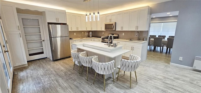 kitchen featuring sink, white cabinets, appliances with stainless steel finishes, and hanging light fixtures