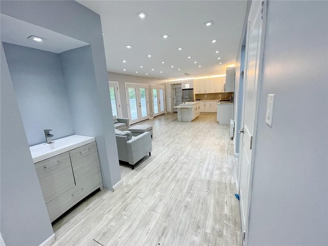 kitchen featuring sink, a center island, light brown cabinetry, and light hardwood / wood-style floors