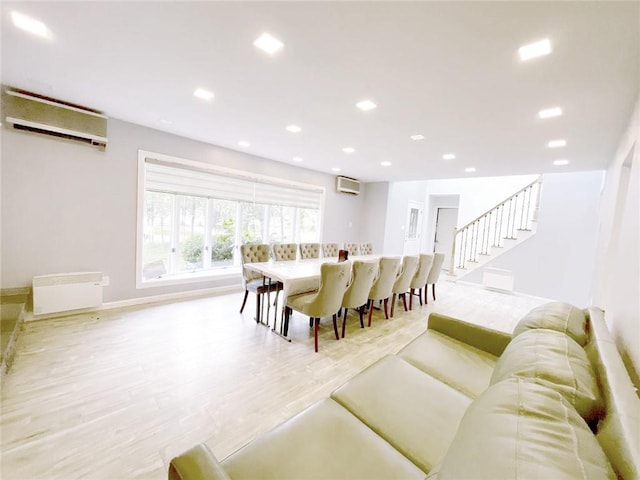 dining space with light hardwood / wood-style floors and a wall mounted air conditioner