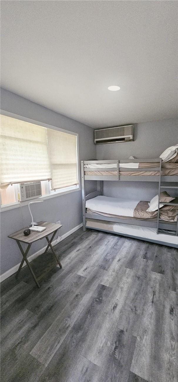 unfurnished bedroom featuring a wall mounted AC, multiple windows, and dark wood-type flooring