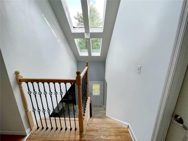 stairs with hardwood / wood-style flooring, a skylight, and a healthy amount of sunlight