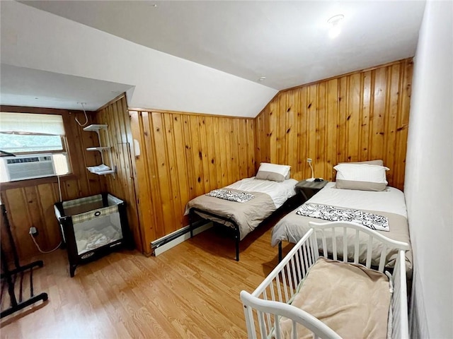 bedroom featuring baseboard heating, wood walls, light wood-type flooring, cooling unit, and lofted ceiling