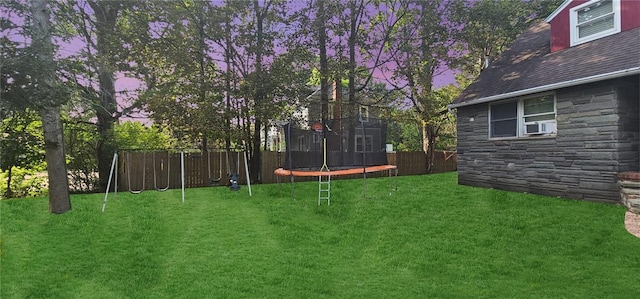 yard at dusk featuring a trampoline