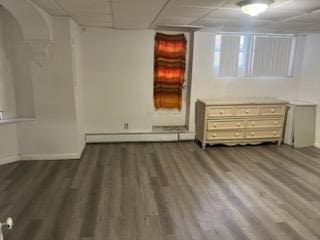 interior space featuring a drop ceiling, dark wood-type flooring, and a baseboard radiator