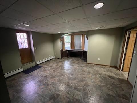 empty room featuring a baseboard radiator and a drop ceiling