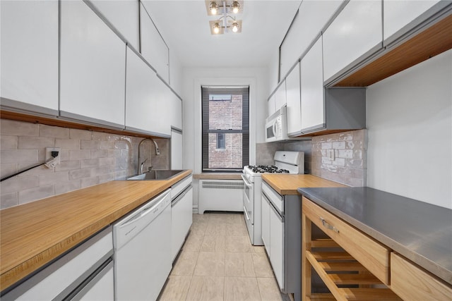 kitchen featuring white appliances, backsplash, white cabinets, sink, and light tile patterned floors