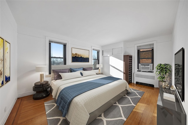 bedroom featuring radiator, light hardwood / wood-style flooring, and cooling unit