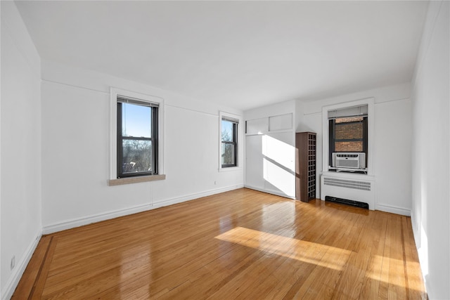 unfurnished room featuring light wood-type flooring, radiator, and cooling unit