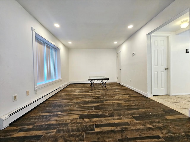 empty room featuring baseboard heating and dark wood-type flooring