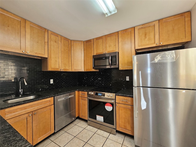 kitchen featuring sink, decorative backsplash, dark stone countertops, light tile patterned floors, and appliances with stainless steel finishes