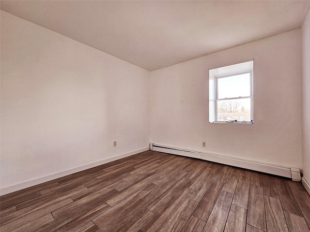 spare room with baseboard heating and dark wood-type flooring