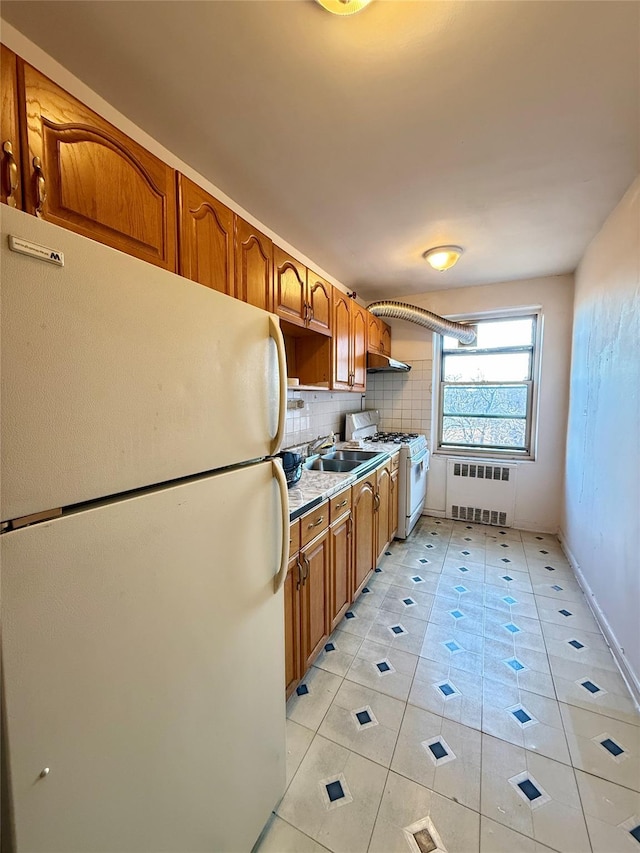 kitchen with radiator heating unit, sink, white appliances, decorative backsplash, and light tile patterned floors