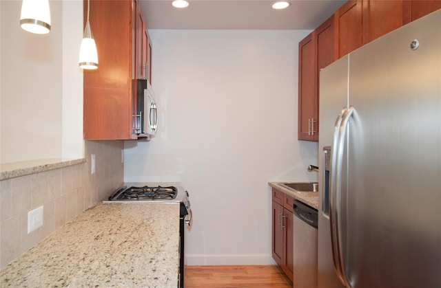 kitchen featuring brown cabinetry, recessed lighting, a sink, appliances with stainless steel finishes, and tasteful backsplash