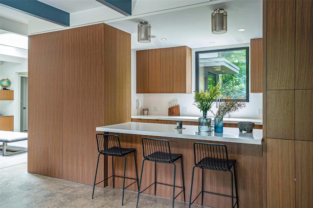 kitchen featuring brown cabinets, light countertops, a breakfast bar area, and modern cabinets