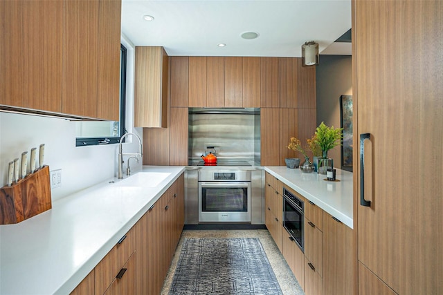 kitchen featuring recessed lighting, light countertops, a sink, modern cabinets, and oven