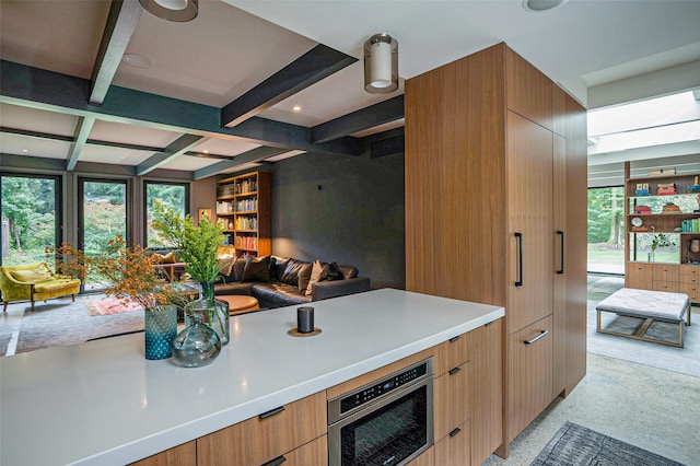 kitchen featuring modern cabinets, open floor plan, beamed ceiling, and light countertops