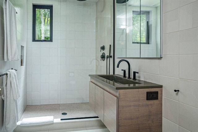 full bath featuring tile walls, a walk in shower, and a sink