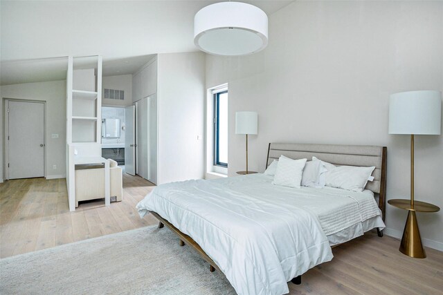 bedroom with baseboards, visible vents, and wood finished floors