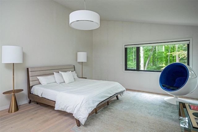 bedroom with lofted ceiling, baseboards, and wood finished floors