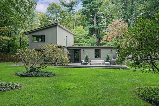 back of property featuring fence, outdoor lounge area, and a lawn