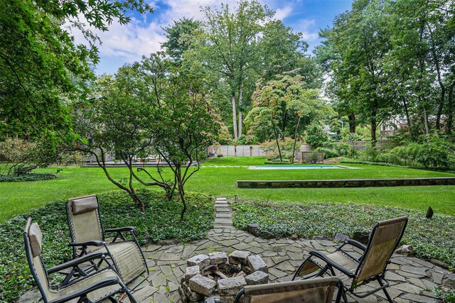 view of property's community with an outdoor fire pit, fence, a lawn, and a patio