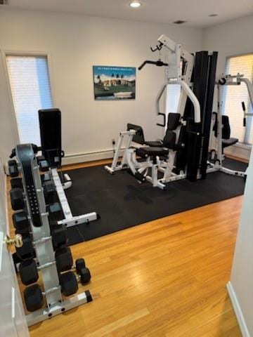 exercise room featuring baseboard heating and wood-type flooring