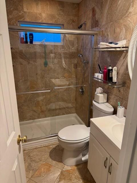 bathroom with tile patterned floors, toilet, a shower with door, vanity, and tile walls