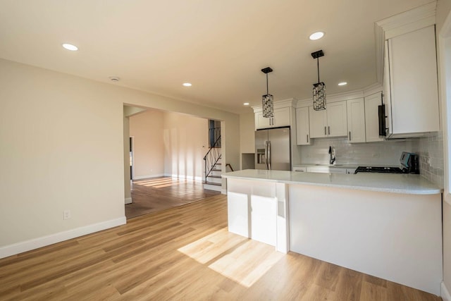 kitchen with light hardwood / wood-style floors, stainless steel fridge, white cabinets, and range