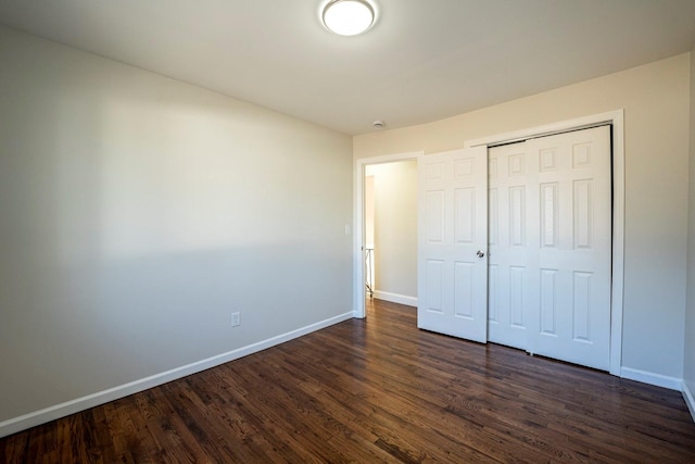 unfurnished bedroom with dark hardwood / wood-style floors and a closet