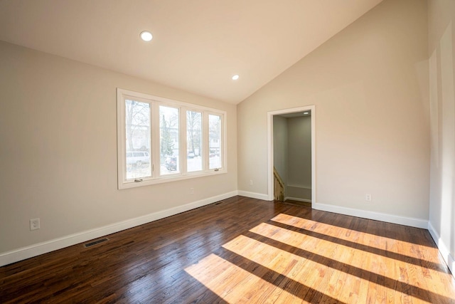 empty room with dark hardwood / wood-style flooring and vaulted ceiling