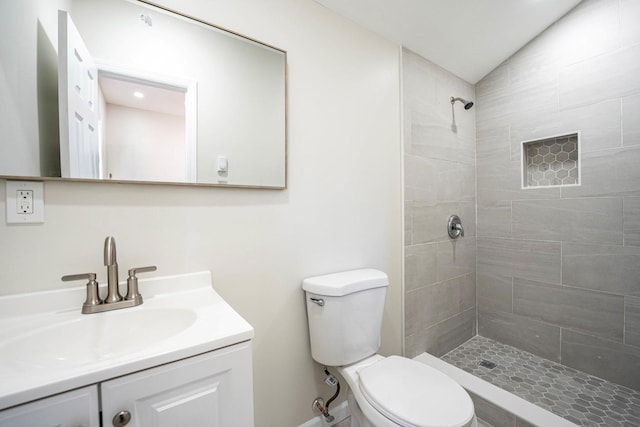 bathroom featuring tiled shower, vanity, and toilet