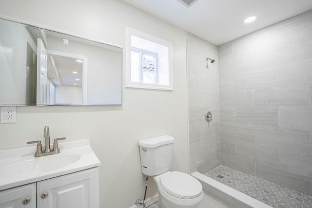 bathroom with a tile shower, vanity, and toilet