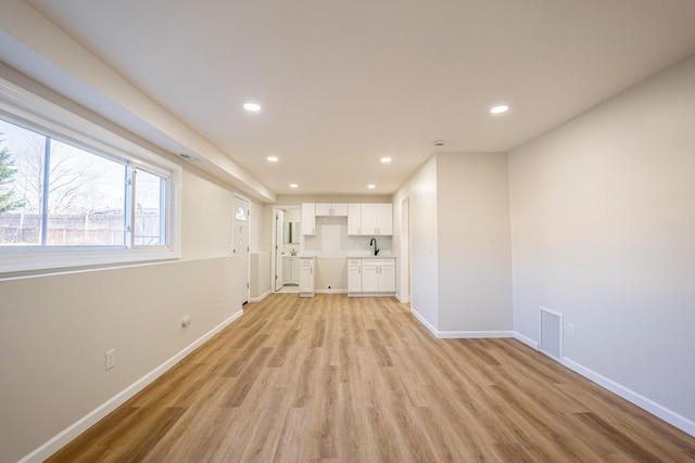 unfurnished living room featuring sink and light hardwood / wood-style flooring