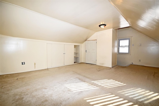 additional living space with built in features, carpet floors, and vaulted ceiling