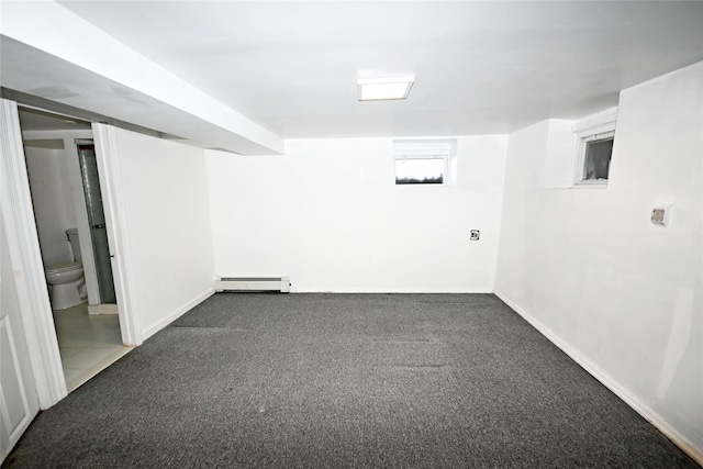 basement featuring dark carpet and baseboard heating