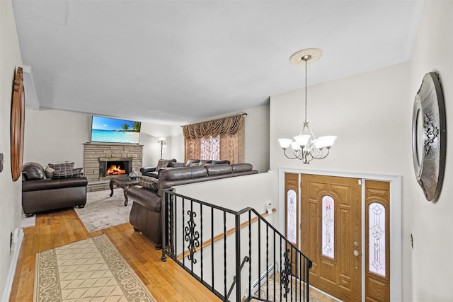 entrance foyer with a fireplace, wood-type flooring, and a notable chandelier