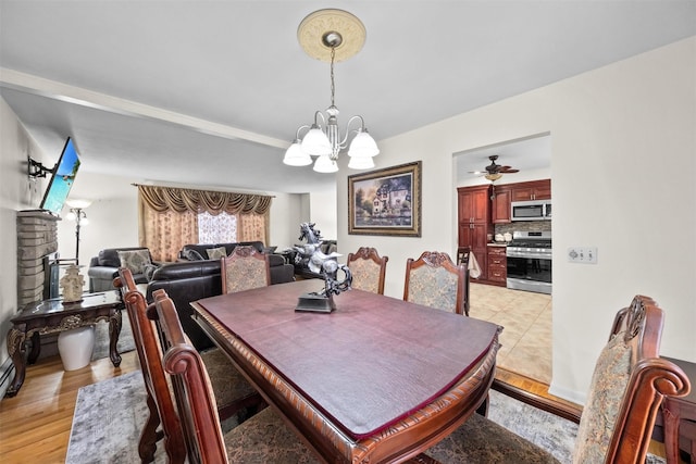 dining room with ceiling fan with notable chandelier and light wood-type flooring