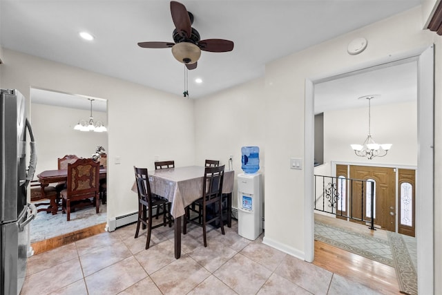 tiled dining room with baseboard heating and ceiling fan with notable chandelier