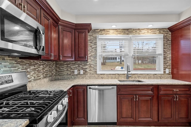 kitchen featuring appliances with stainless steel finishes, light stone counters, and sink