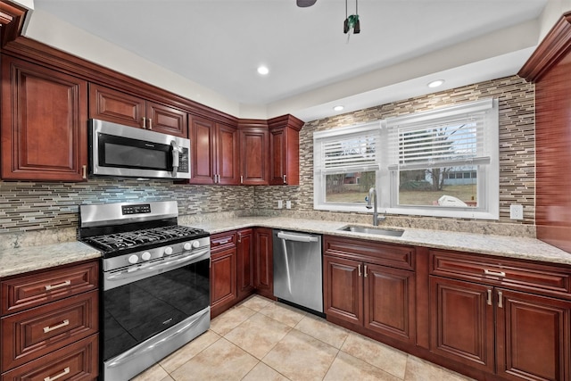 kitchen featuring decorative backsplash, sink, light stone counters, and appliances with stainless steel finishes