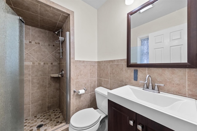 bathroom with an enclosed shower, vanity, toilet, and tile walls