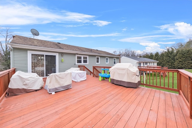 wooden terrace featuring area for grilling and a yard