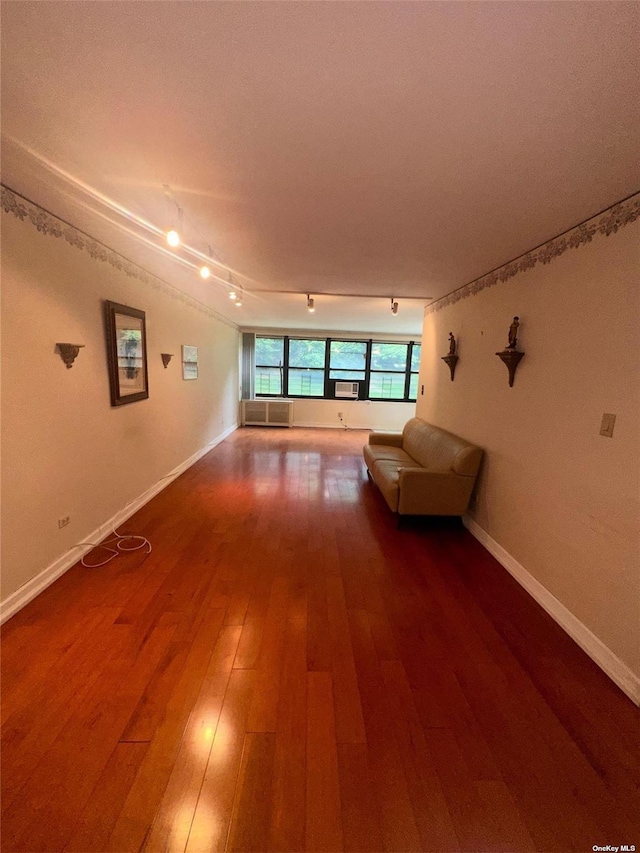 unfurnished living room featuring rail lighting and hardwood / wood-style flooring