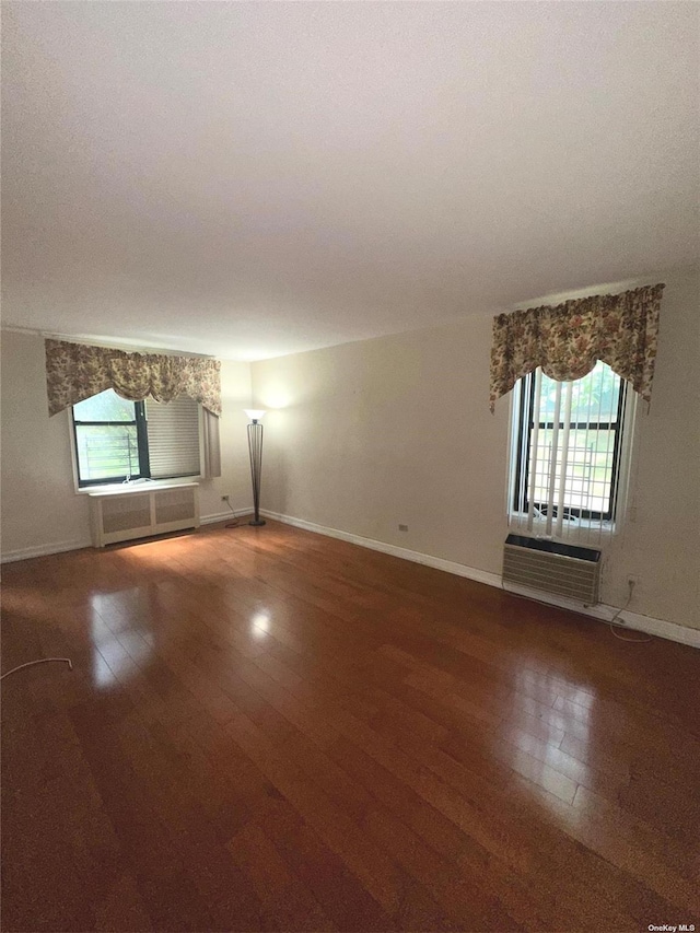 unfurnished room featuring a wall mounted AC, hardwood / wood-style floors, and plenty of natural light