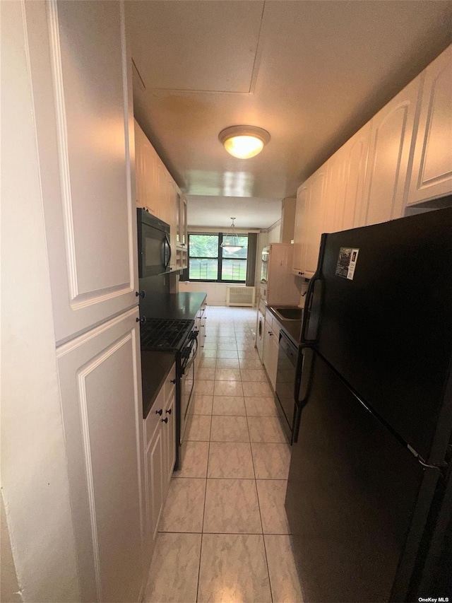 kitchen with white cabinets, black appliances, and light tile patterned floors